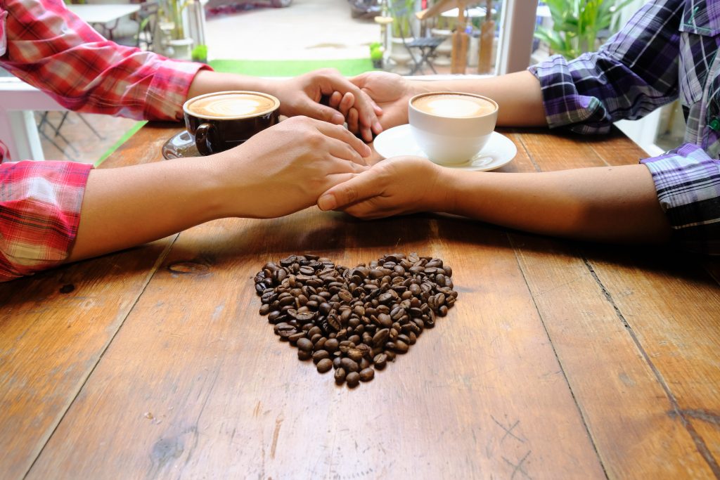 Invertir en el Futuro del Café Colombiano: Oportunidades y Beneficios de Apoyar Nuestra Expansión 🚀💼 4 couple love holding hands with coffee wooden table